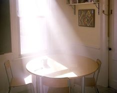 a table and chairs in front of a window with sunlight coming through the blinds on it