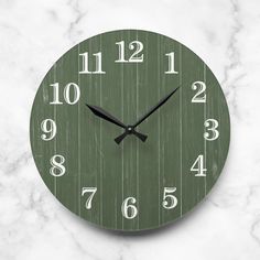 a green clock with white numbers is on a marble surface and looks like it's made out of wood