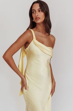 a woman wearing a yellow dress with one shoulder and an asymmetrical neckline