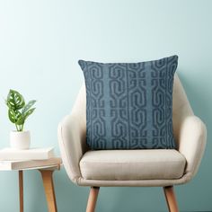 a chair with a pillow on it next to a potted plant and a blue wall