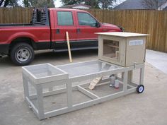 a red pick up truck parked next to a metal structure with a box on it's back end