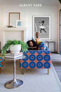 a woman laying on a couch in a living room next to a table with a potted plant