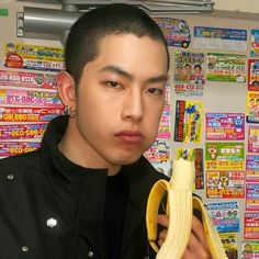 a young man is holding a banana in front of a wall covered with stickers