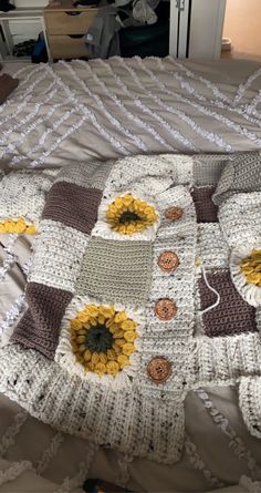 a crocheted blanket with sunflowers on it sitting on top of a bed