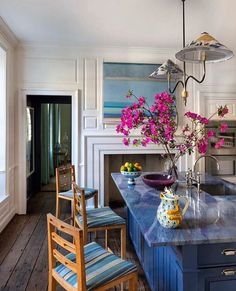 a kitchen with blue counter tops and wooden chairs in front of an island that has flowers on it