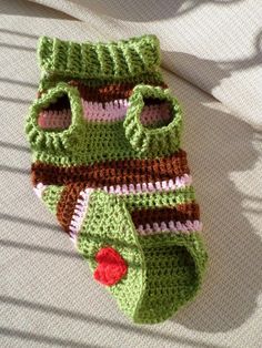 a crocheted green and brown bag sitting on top of a bed