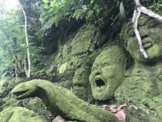 some very big statues in the middle of a hill covered in green mossy plants