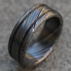 a wedding ring that has been made with black and white stripes on it, sitting on the ground