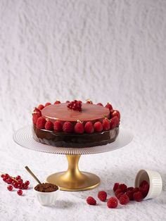 a chocolate cake with raspberries on top and other desserts around it,