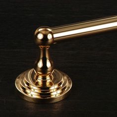 a golden metal object sitting on top of a wooden table next to a black background