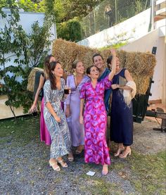 four women standing in front of hay bales with one woman holding her hand up