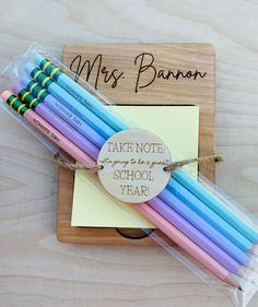 several colored pencils are wrapped in cellophane and tied to a wooden plaque