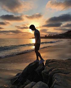 a man standing on top of a rock next to the ocean