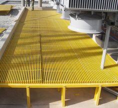 a yellow bench sitting on top of a cement floor next to a machine and machinery