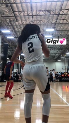 a woman standing on top of a basketball court wearing white and black shorts with the number 2 on it