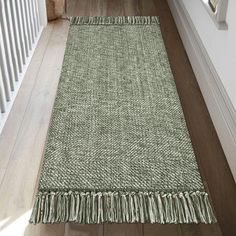 a green rug with fringes on the floor