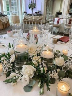 the table is set with candles, flowers and greenery for an elegant wedding reception