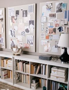 a white bookcase with many books and pictures on the wall next to a lamp