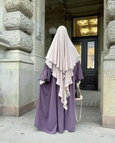 a woman dressed in a purple outfit is walking down the street with her back turned to the camera