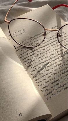 an open book with glasses on top of it