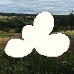 an image of a pixelated object in the middle of a field with flowers and grass