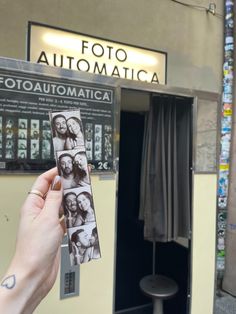 a person holding up an item in front of a photo booth with pictures on it