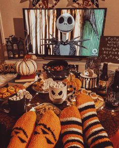 a table topped with lots of halloween treats and snacks on top of it next to a flat screen tv