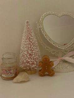 a small white christmas tree next to a gingerbread man and a jar of honey