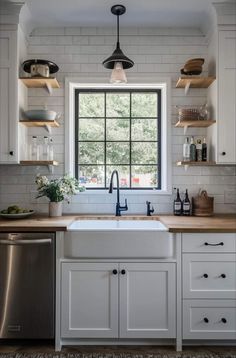 a kitchen with white cabinets and open shelving above the sink is seen in this image