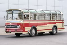 an old red and white bus parked in front of a building