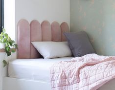 a bed with pink headboard and pillows on it