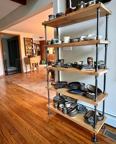 the shelves are filled with plates and pans on wooden flooring in an open living room