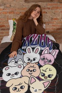 a woman sitting on top of a bed covered in cartoon character blanketes and pillows