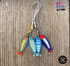 three colorful birds are hanging from a keychain on a wooden surface with the words blou dere