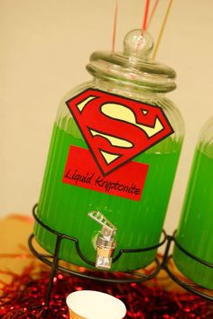 two jars filled with liquid sitting on top of a table next to candles and toothbrushes