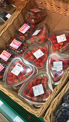 strawberries are arranged in heart - shaped bowls on display at a grocery store for sale