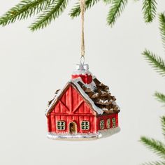 a red house ornament hanging from a christmas tree