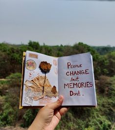 someone holding up a book with words on it in front of some trees and bushes