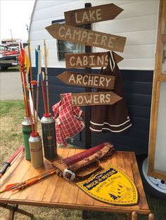 a wooden table topped with lots of different types of camping signs on top of it