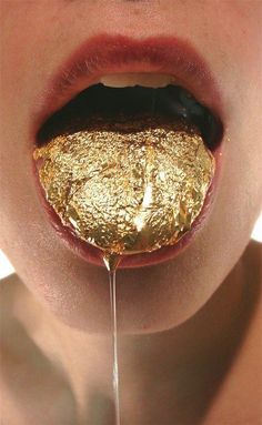 a young child with gold flakes on his tongue