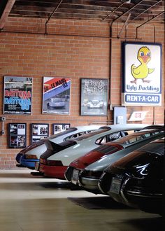 there are many cars parked in the showroom with posters on the wall behind them