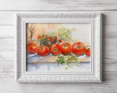 a painting of tomatoes in a white frame on a wooden table with flowers and greenery