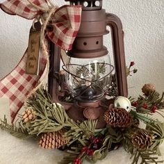 an old fashioned lantern is adorned with pine cones, evergreens and other holiday decorations