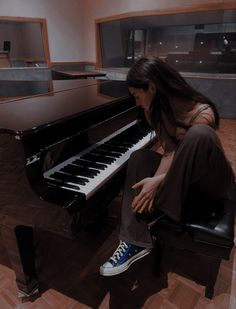 a woman sitting in front of a black piano