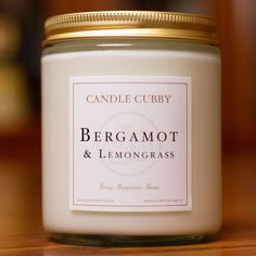 a candle is sitting on a table with a label that says bergamot and lemongrass