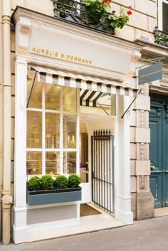 an outside view of a store front with flowers in the window and plants on the windowsill