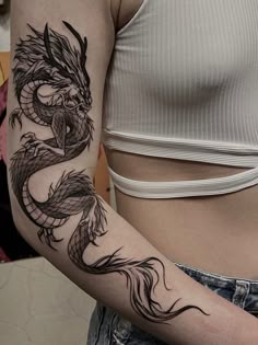 a woman's arm with a dragon tattoo on the left side of her body