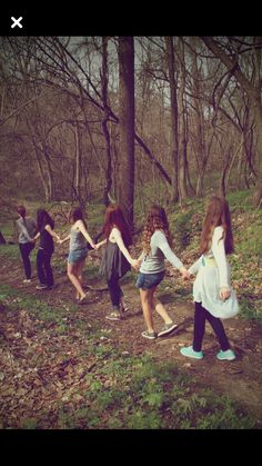 a group of young people holding hands in the woods