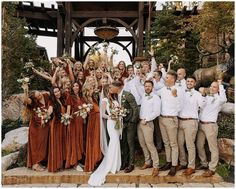 a group of people standing next to each other in front of a wooden structure with flowers