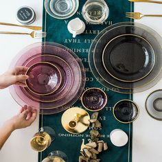 the table is set with plates, silverware and gold rimmed glasses on it